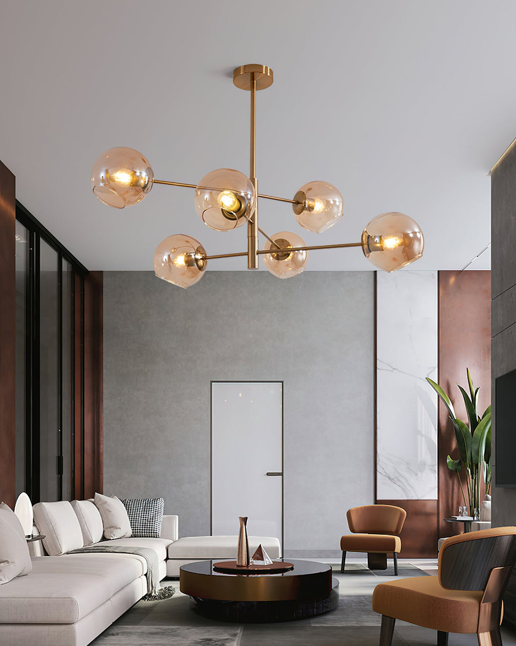 Amber globes lit on a branching Clérachic chandelier in an open living space with a white sofa, a round coffee table and tan chairs.