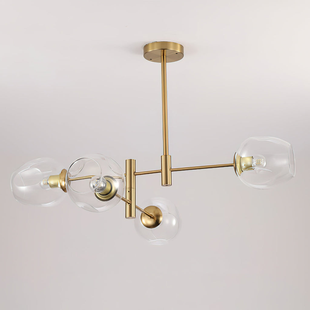 Wide view of the clear glass globes and brass tubes of this Clérachic chandelier, hung from a long rod against a pale wall.