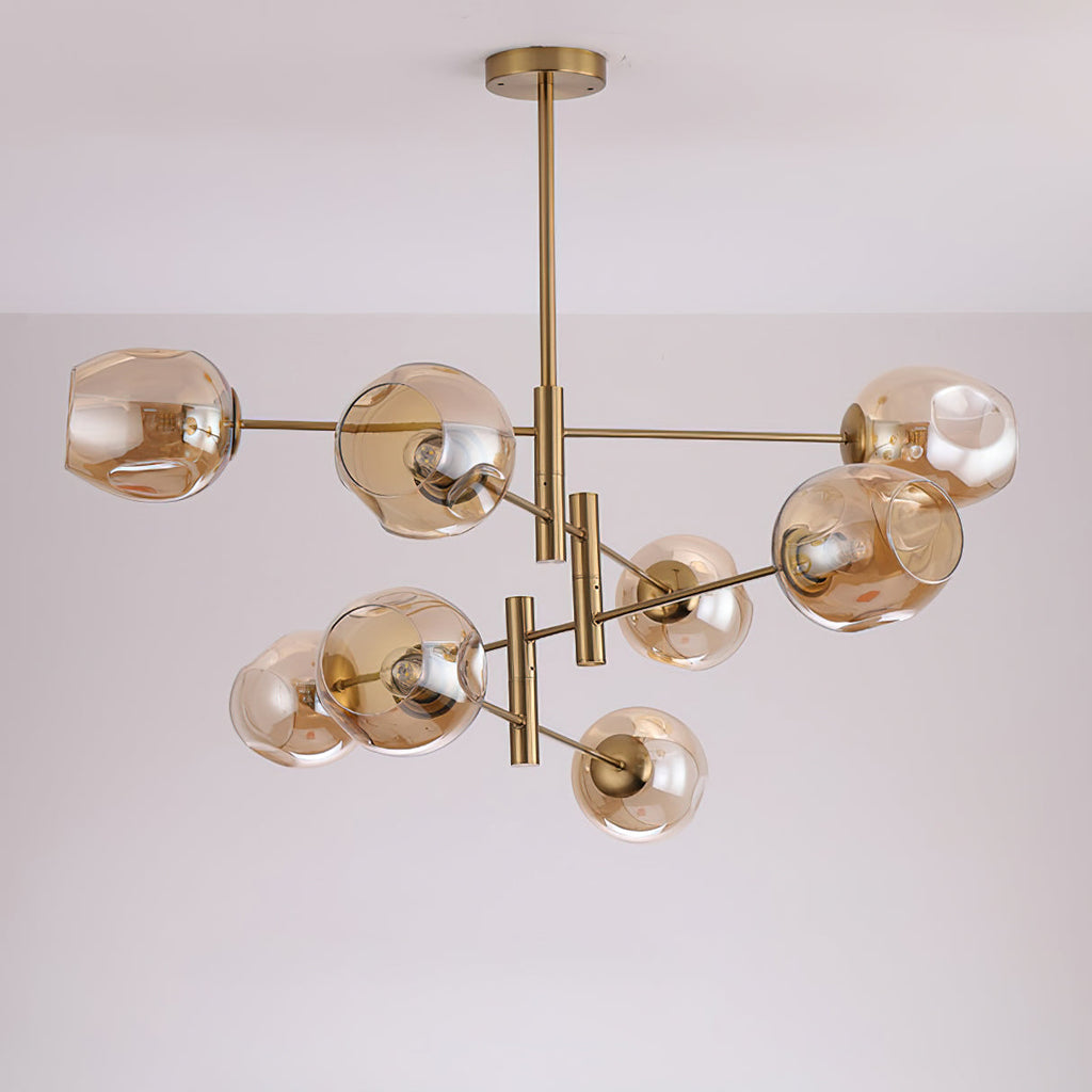 Amber glass globes in an uneven, dimpled shape on this Clérachic gold chandelier, shown from below against a pale ceiling.