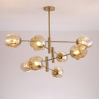 Lit amber globes on the branching gold arms of this Clérachic chandelier, photographed against a soft grey-lilac ceiling.