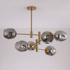 Unlit smoky grey glass globes with dimpled sides on a gold-finish Clérachic chandelier, seen against a pale ceiling.