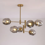 Smoky grey globes lit on a gold-finish Clérachic chandelier, the bulbs showing through the dimpled glass.