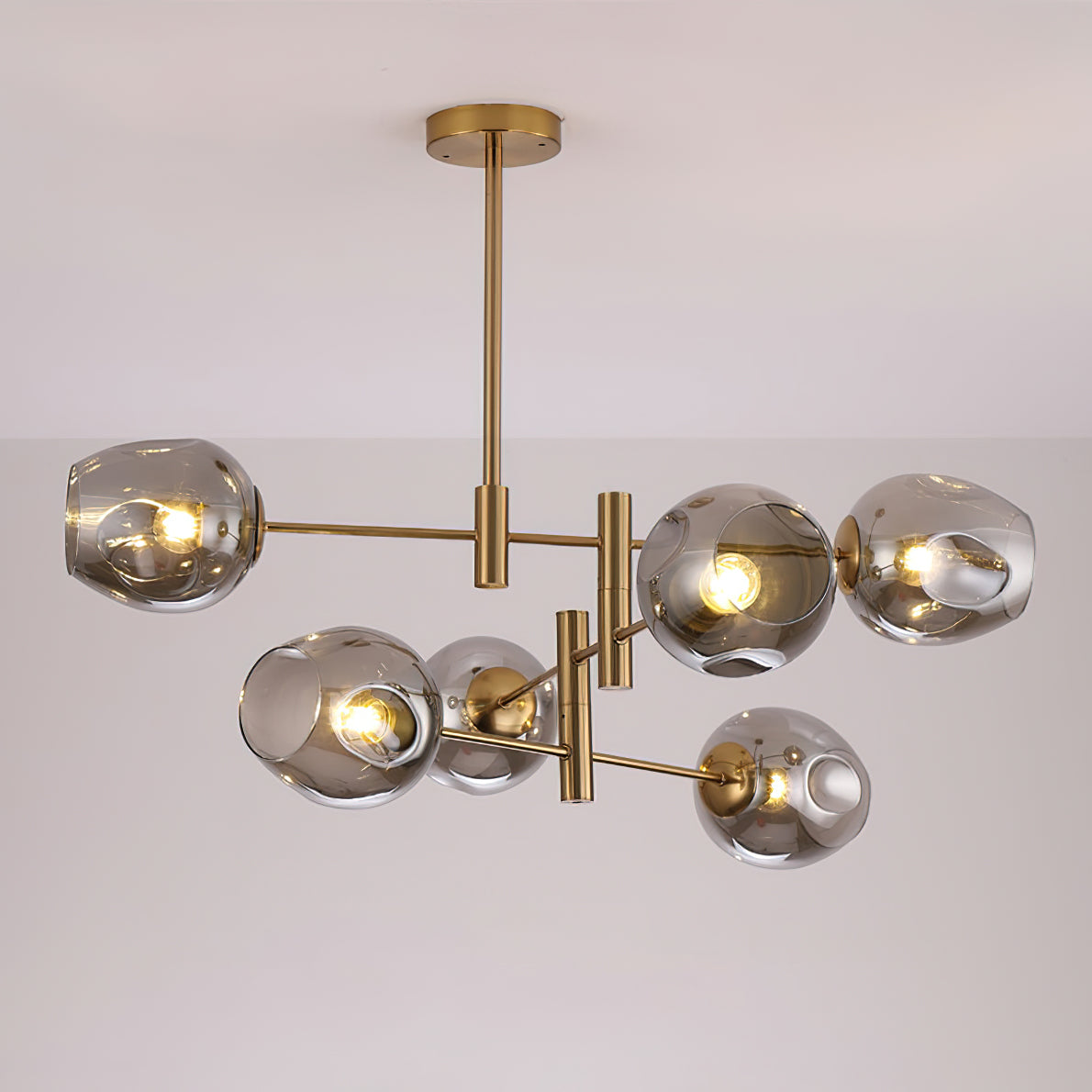 Smoky grey globes lit on a gold-finish Clérachic chandelier, the bulbs showing through the dimpled glass.