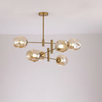Amber-toned glass globes lit on a smaller gold-finish Clérachic chandelier hung from a slim rod, against a soft grey wall.