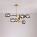 Smoky grey dimpled globes lit on the gold arms of this Clérachic chandelier, seen below a pale ceiling.