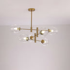 Clear glass globes with bulbs visible on a gold-finish Clérachic chandelier, lit and photographed against a pale ceiling.