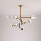 Clear dimpled glass globes on the layered gold arms of a larger Clérachic chandelier, lit against a pale wall.