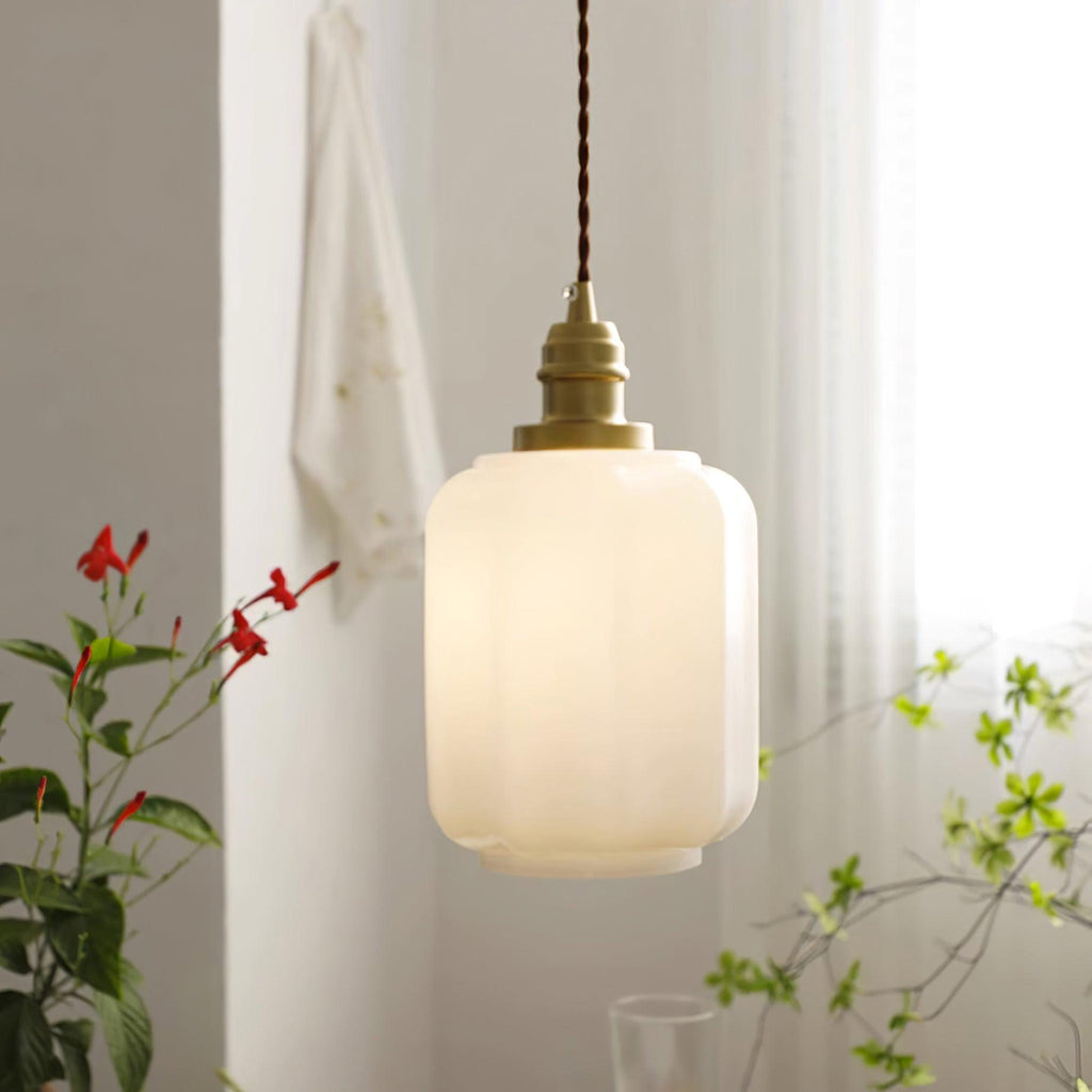 The Clérachic glass globe pendant light glows warm white beside a sheer-curtained window framed by red flowering plants.