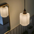 The Clérachic glass globe pendant light reflected in a brass-framed bathroom mirror while lit warm white.