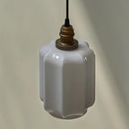 Close-up product shot of the Clérachic glass globe pendant light's faceted opal glass shade and brass cap.