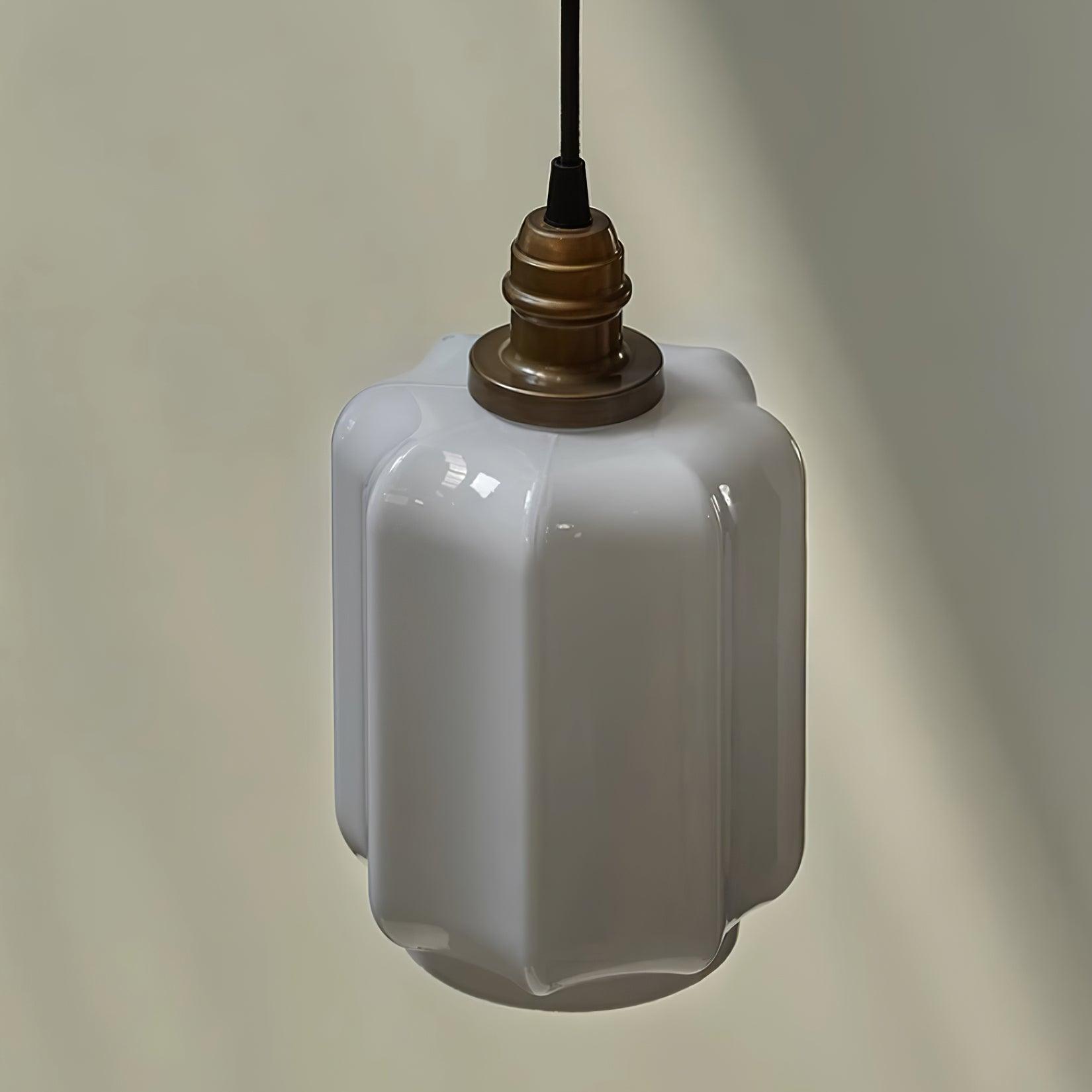 Close-up product shot of the Clérachic glass globe pendant light's faceted opal glass shade and brass cap.