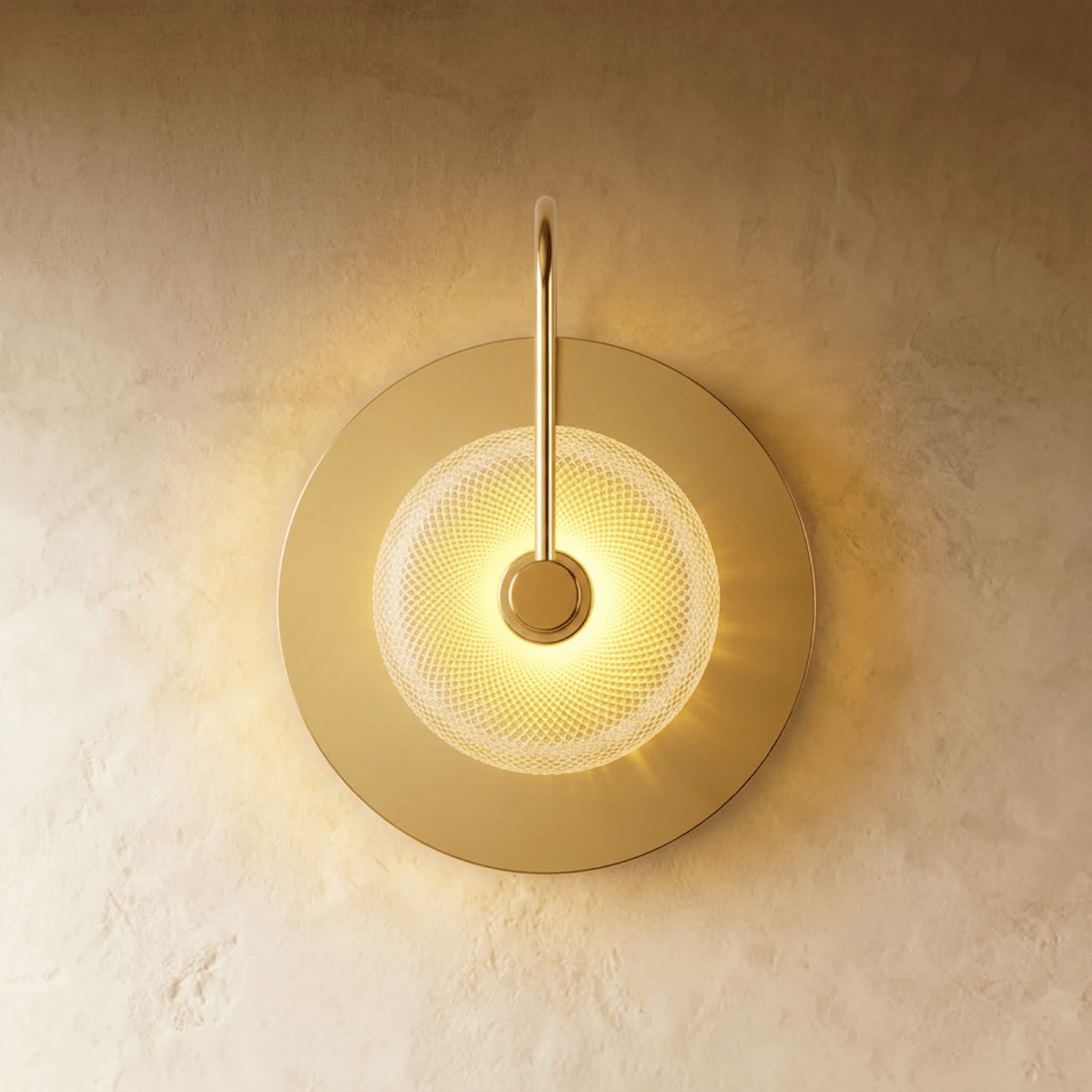 Clérachic single-head wall lamp with a brass disc backplate, a curved brass arm and a lit clear textured glass dome.