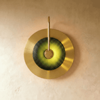 Clérachic single-head brass wall lamp with a dark green textured glass dome glowing lime, on a round brass backplate.