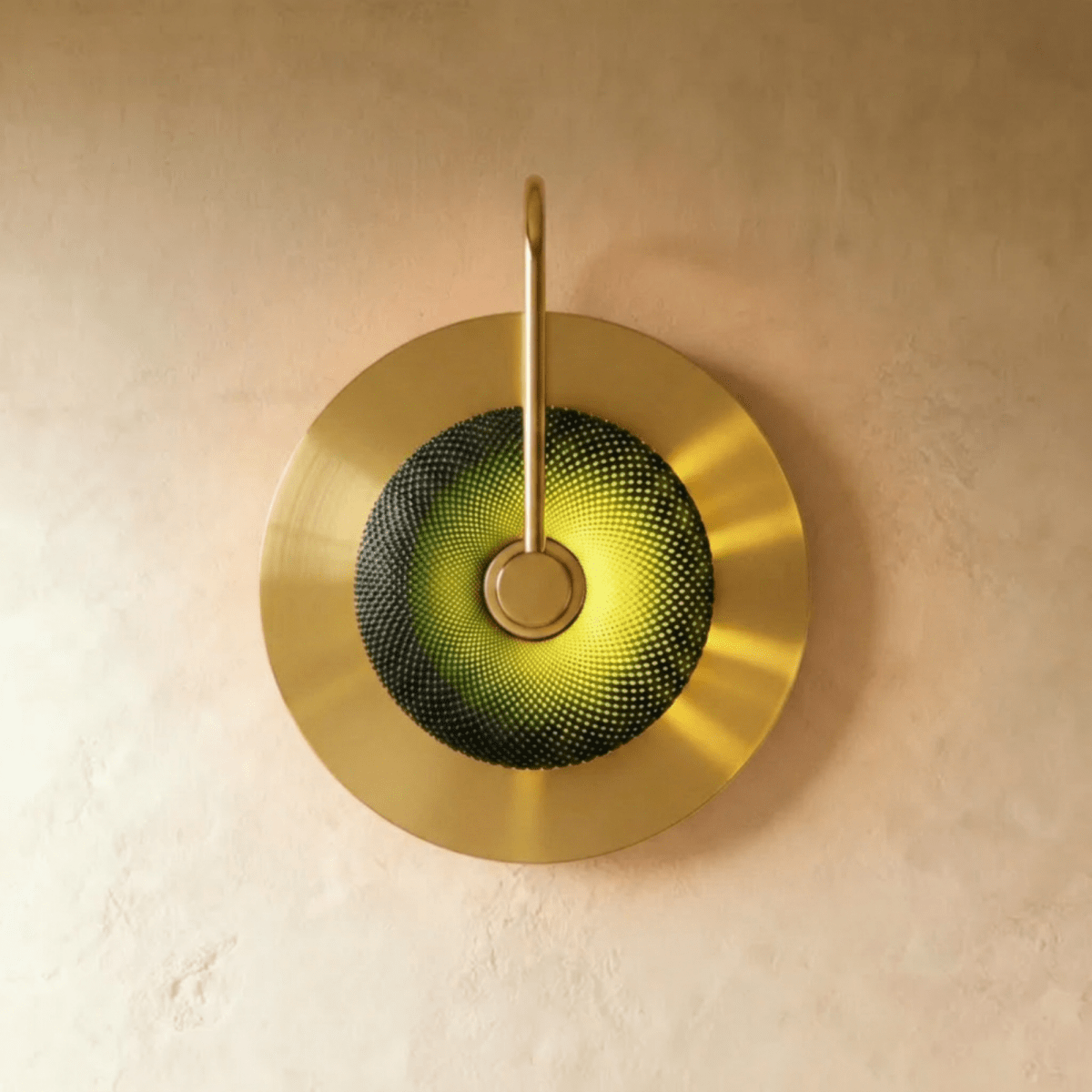 Clérachic single-head brass wall lamp with a dark green textured glass dome glowing lime, on a round brass backplate.