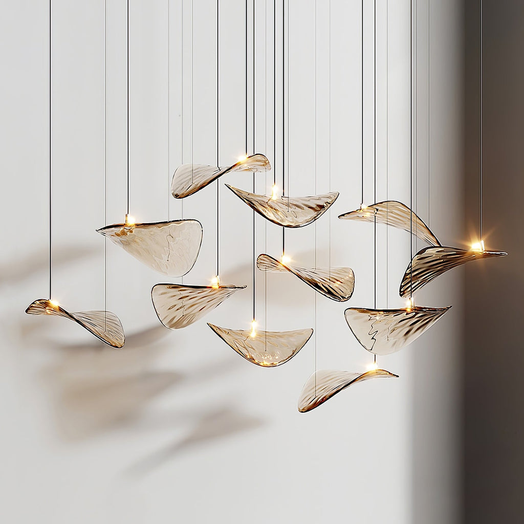 Close view of a dozen amber glass leaves, each with its own small light, hanging at different heights from this Clérachic pendant.