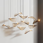 Close view of a dozen amber glass leaves, each with its own small light, hanging at different heights from this Clérachic pendant.