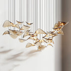 Amber glass leaves, some folded up at the edges, hang low in a lit cluster from this Clérachic pendant light.