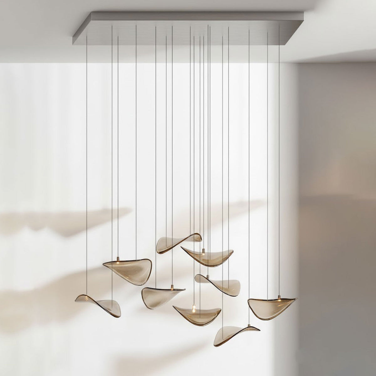 Rectangular chrome canopy with amber glass leaves hanging in a loose group on long cables, from this Clérachic pendant.