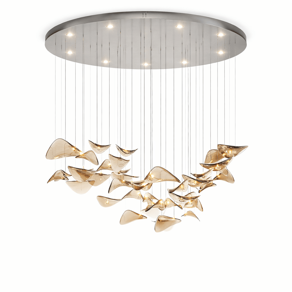 Chrome canopy with small downlights above a wide hanging group of amber glass leaves, from this Clérachic pendant, on white.