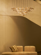 Dim room with a curved cream stair and a low sofa, with a Clérachic amber leaf pendant glowing high in the background.