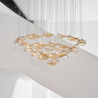 Amber glass leaves in tiered rings, from this Clérachic pendant, hung against the white curve of a staircase.