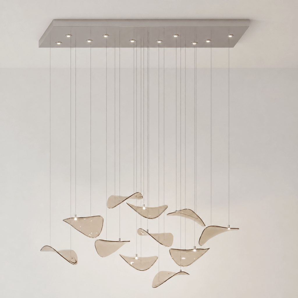 Rectangular chrome canopy with small lights and a small group of amber glass leaves on cables, on a cream wall, from Clérachic.