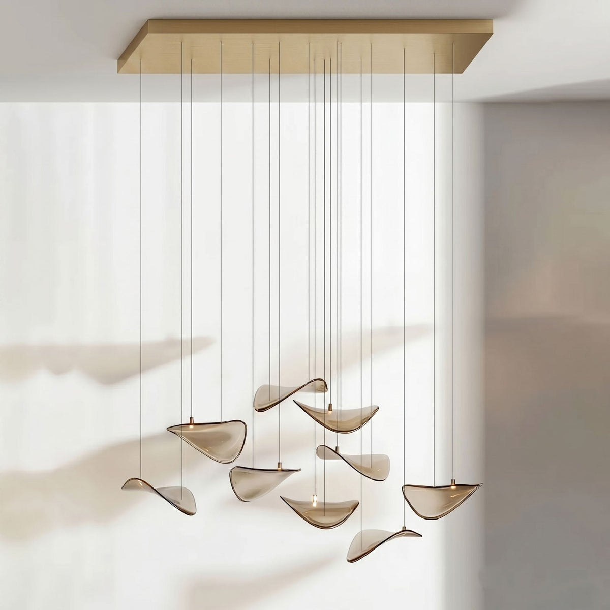 Long gold canopy with a loose group of amber glass leaves hanging from fine cables, from this Clérachic pendant.