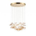 Gold round canopy with long cable drops and a layered group of rounded amber glass leaves, from this Clérachic pendant, on white.