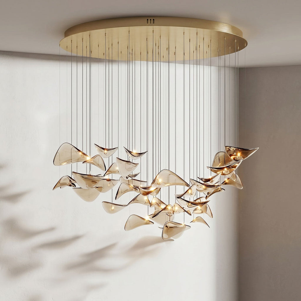 Round gold canopy over a wide, lit cluster of amber glass leaves, shown in a pale room with soft shadows, from Clérachic.