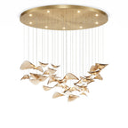 Large round gold canopy with small downlights above a wide hanging group of amber glass leaves, from Clérachic, on white.
