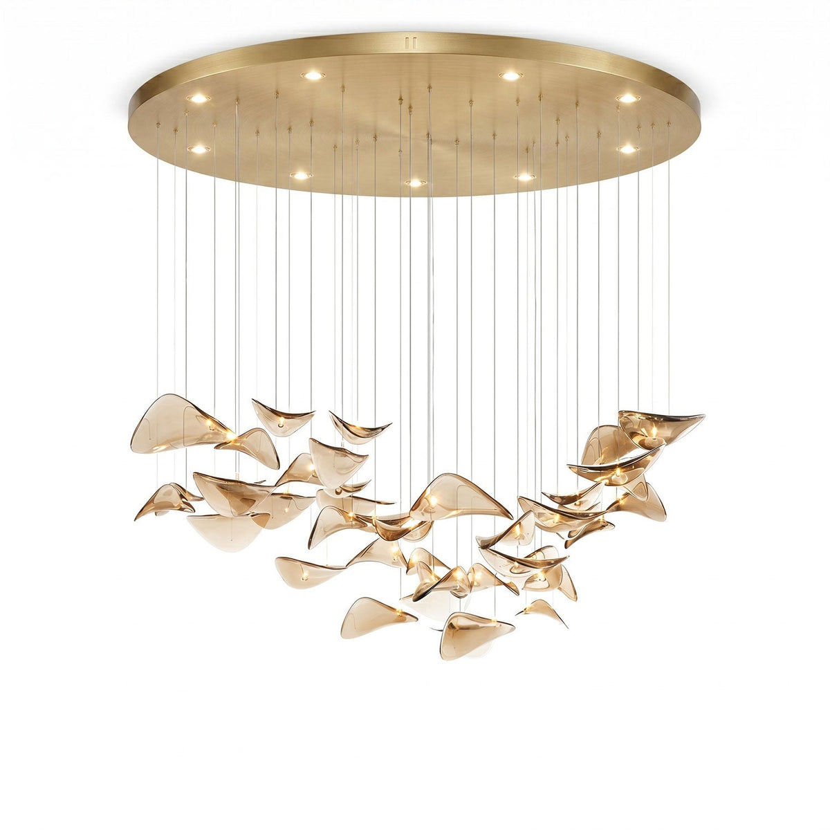 Large round gold canopy with small downlights above a wide hanging group of amber glass leaves, from Clérachic, on white.