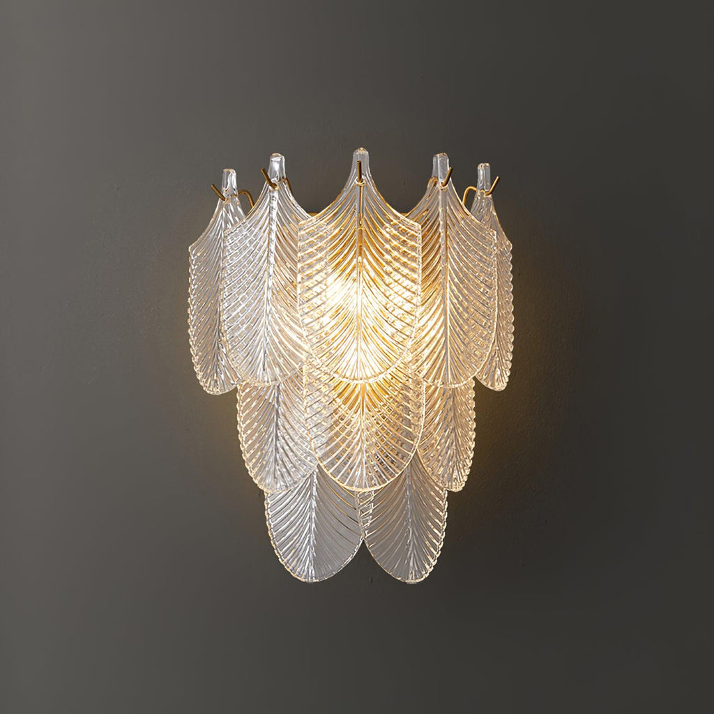Close view of the lit Clérachic wall light on a dark grey wall, its tiers of clear ribbed glass leaves glowing warm at the centre.