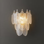 Close view of the lit Clérachic wall light on a dark grey wall, its tiers of clear ribbed glass leaves glowing warm at the centre.