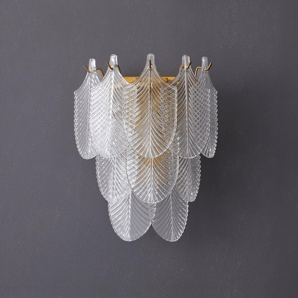 Front view of the unlit Clérachic wall light on a grey wall, three tiers of ribbed glass leaves with brass hooks along the top.