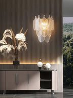 Clérachic wall light on a dark slatted wall above a low sideboard, with pampas grass, white flowers and a view of forest beyond.