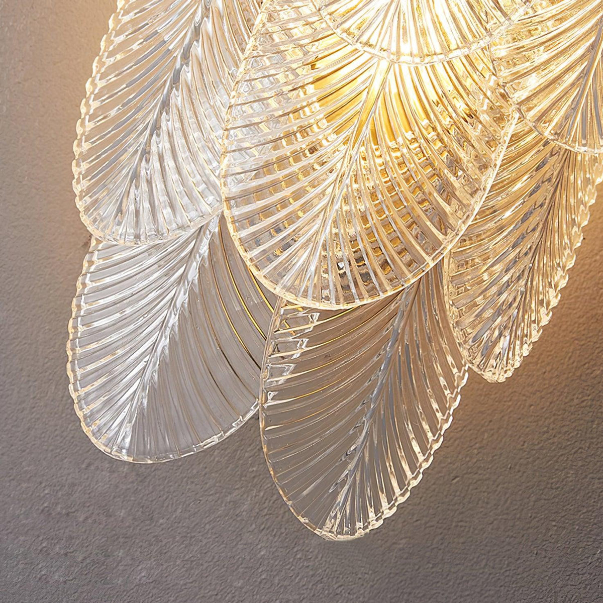 Close view of the clear ribbed glass leaves on this Clérachic wall light, warmly lit from within.