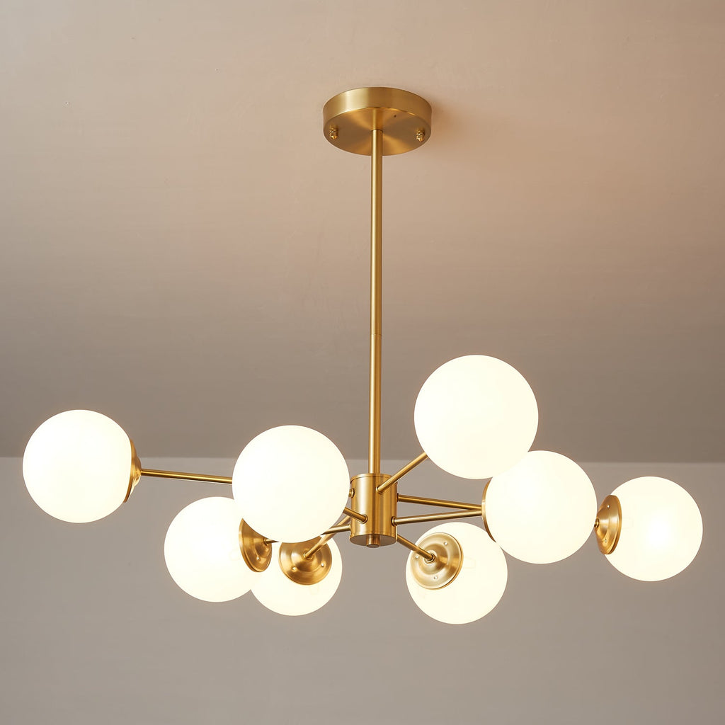 Close, angled view of lit glass orbs and the round brass canopy of this Clérachic chandelier.