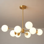Close, angled view of lit glass orbs and the round brass canopy of this Clérachic chandelier.