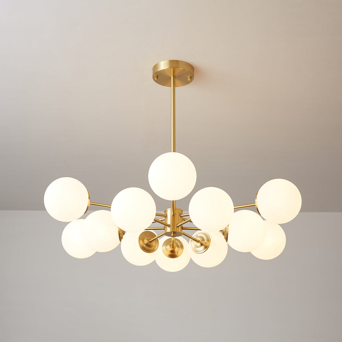 Brass-armed Clérachic chandelier with warm-glowing frosted orbs spread evenly around its hub.