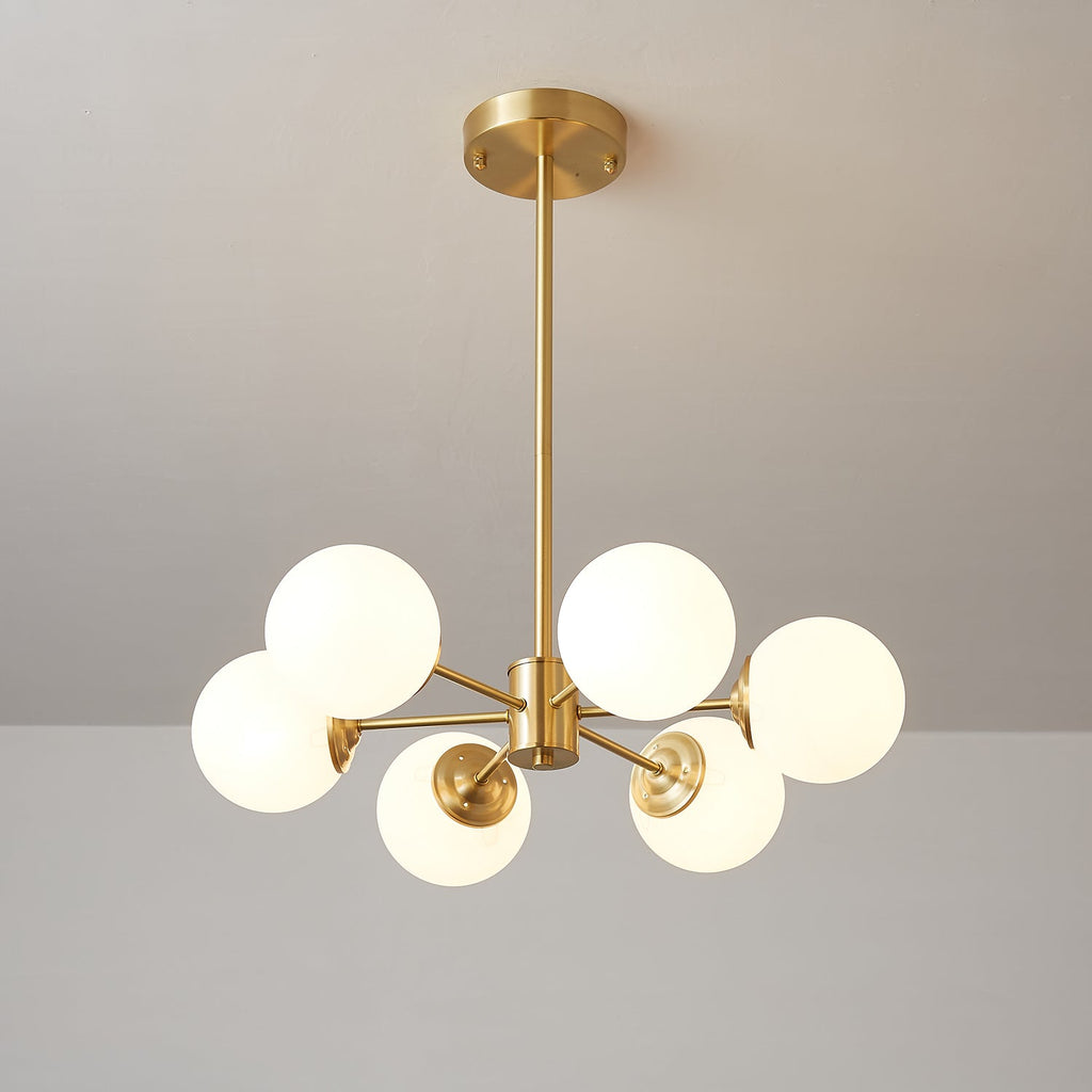 Compact Clérachic chandelier with five large lit frosted orbs, a brass hub and a short drop rod.