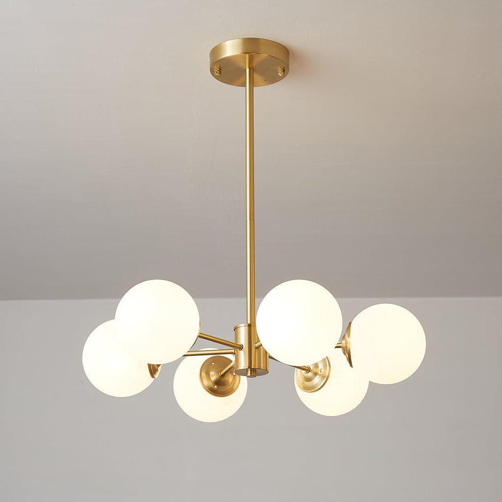 A Clérachic chandelier with six lit orbs on short brass arms, seen from a low angle with its canopy above.
