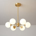 Six-orb Clérachic chandelier with warm-glowing frosted glass, centred on its brass stem on a taupe wall.