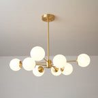 A Clérachic chandelier with lit frosted orbs on uneven brass arms, one globe set high on the left.