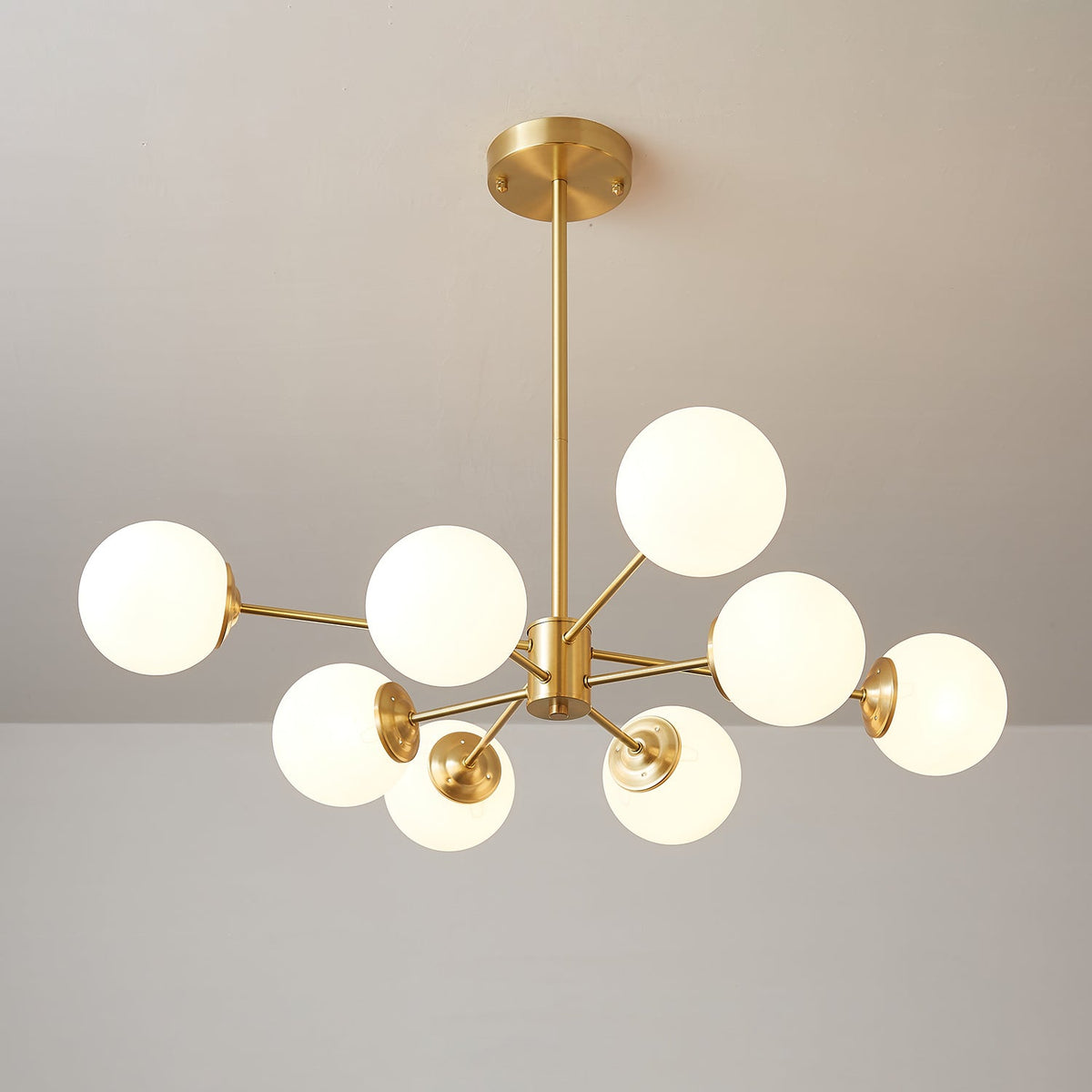 Brass chandelier with glowing orbs on arms of varied length, a Clérachic light with a long drop rod.