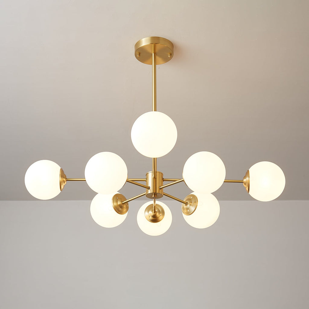 Clérachic chandelier with lit orbs fanned around a brass centre, one orb raised above the others.
