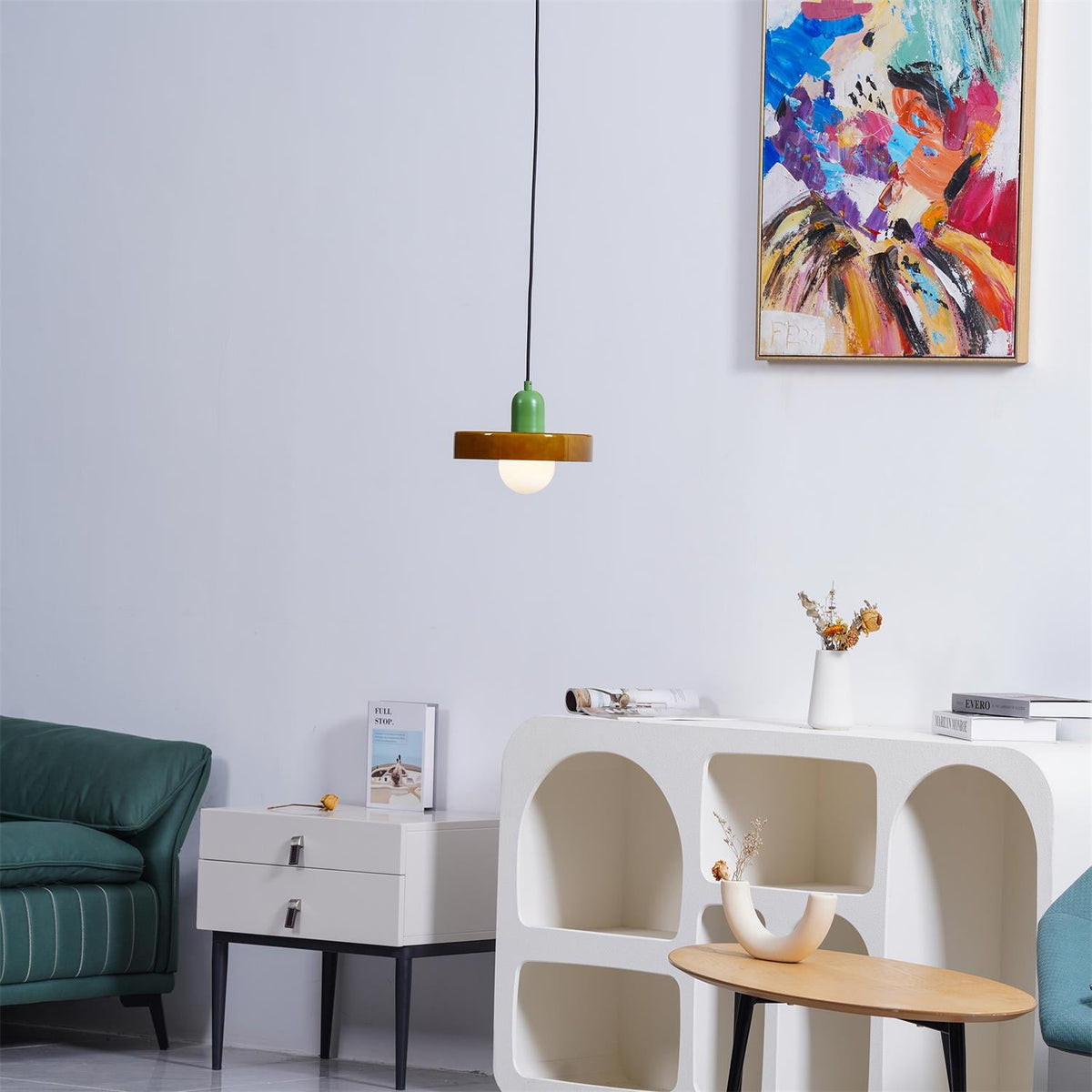 A small olive-green disc pendant with a green cap hangs beside the abstract painting and a teal sofa, a Clérachic accent in a living room.