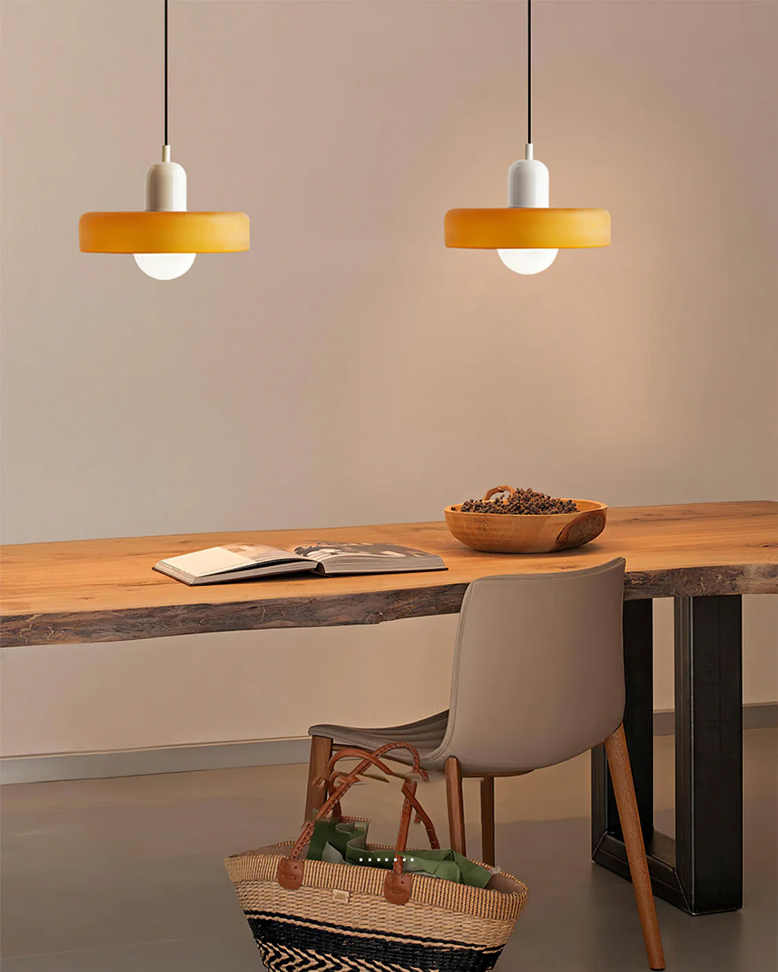 A white-capped disc and a second orange disc glow warm above a live-edge wooden desk and a grey chair, from Clérachic.