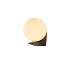 Clérachic wall light on white, its glowing glass orb on a wooden bracket with a darker underside seen from a low angle.