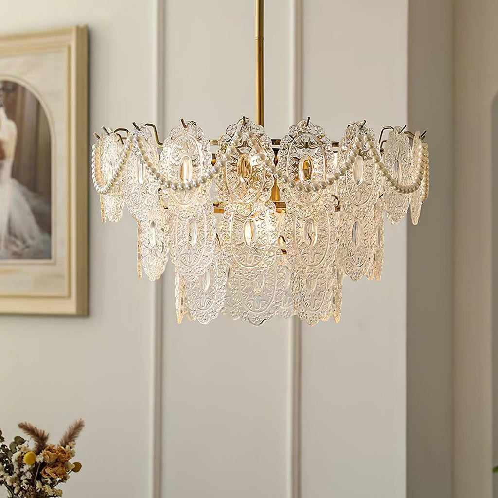 Clérachic chandelier with layered patterned glass panels and draped pearl strands, hanging against a panelled wall and a framed painting.