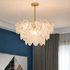 Lit Clérachic glass chandelier with a gold stem, in a room with a deep blue wall and grey curtains.